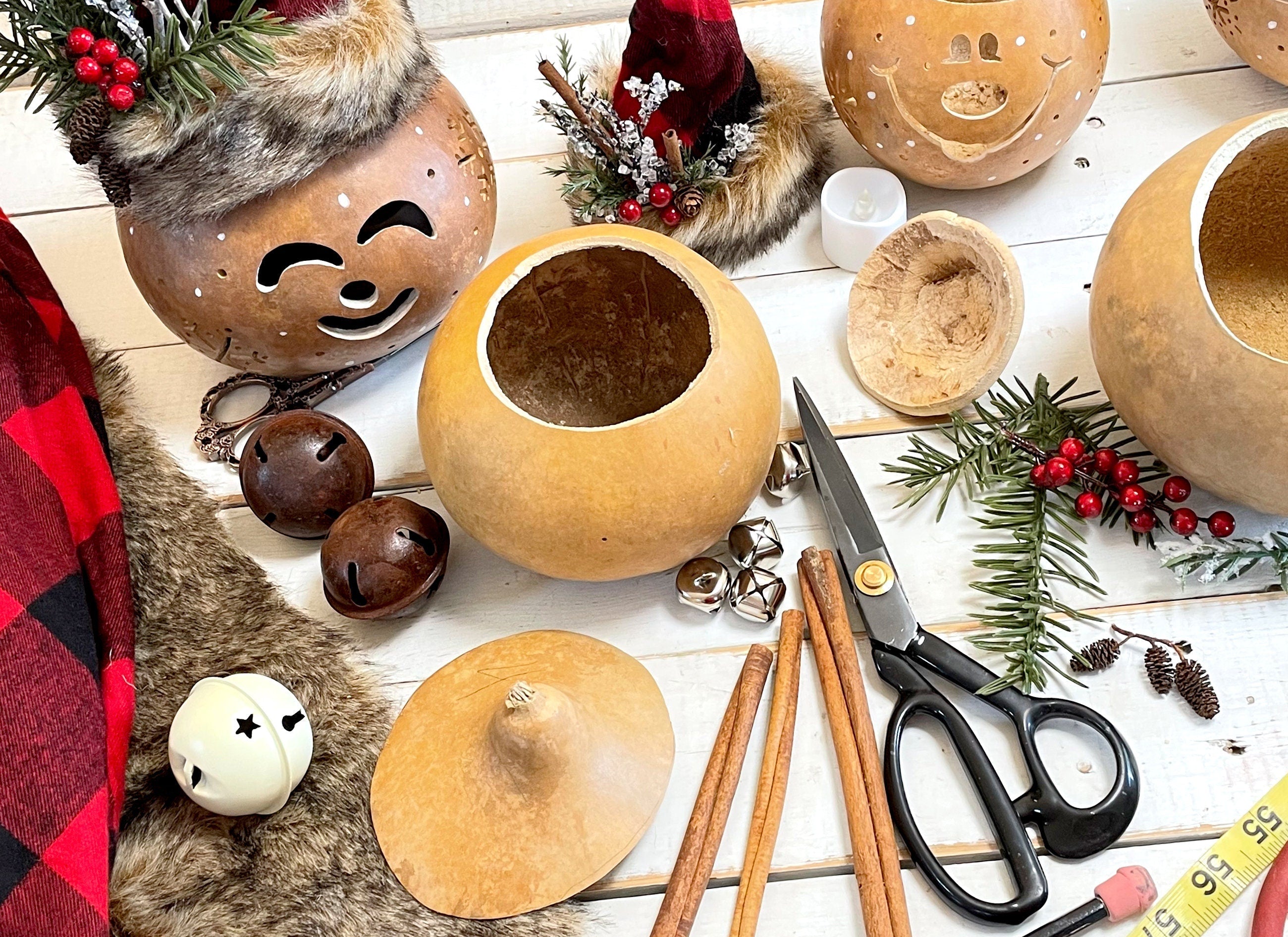 Decorative items including gourds, ribbons, and scissors on a white surface with a red plaid fabric.