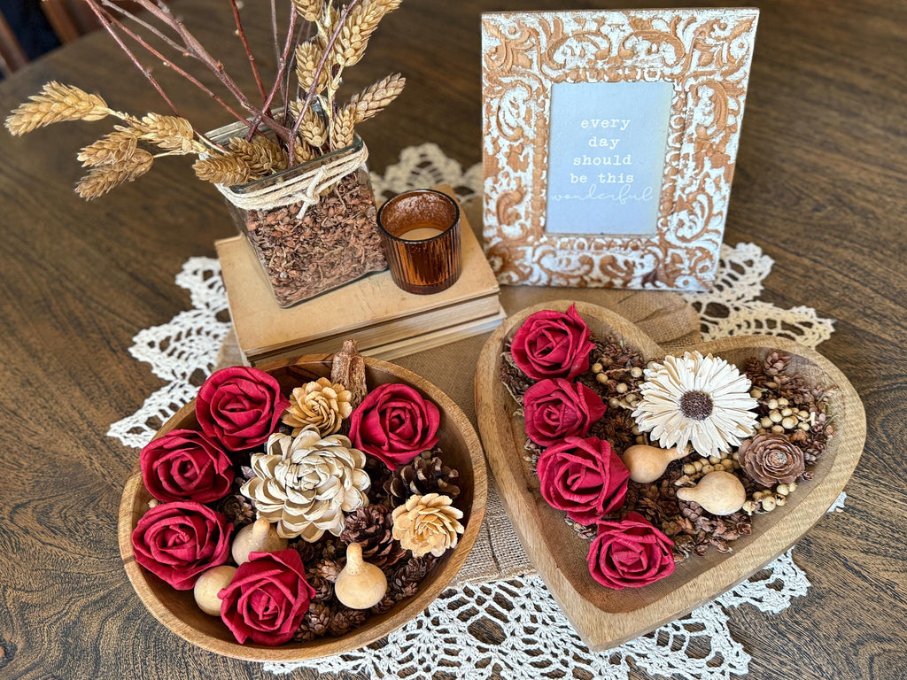 Decorative heart-shaped bowl with flowers on a wooden table