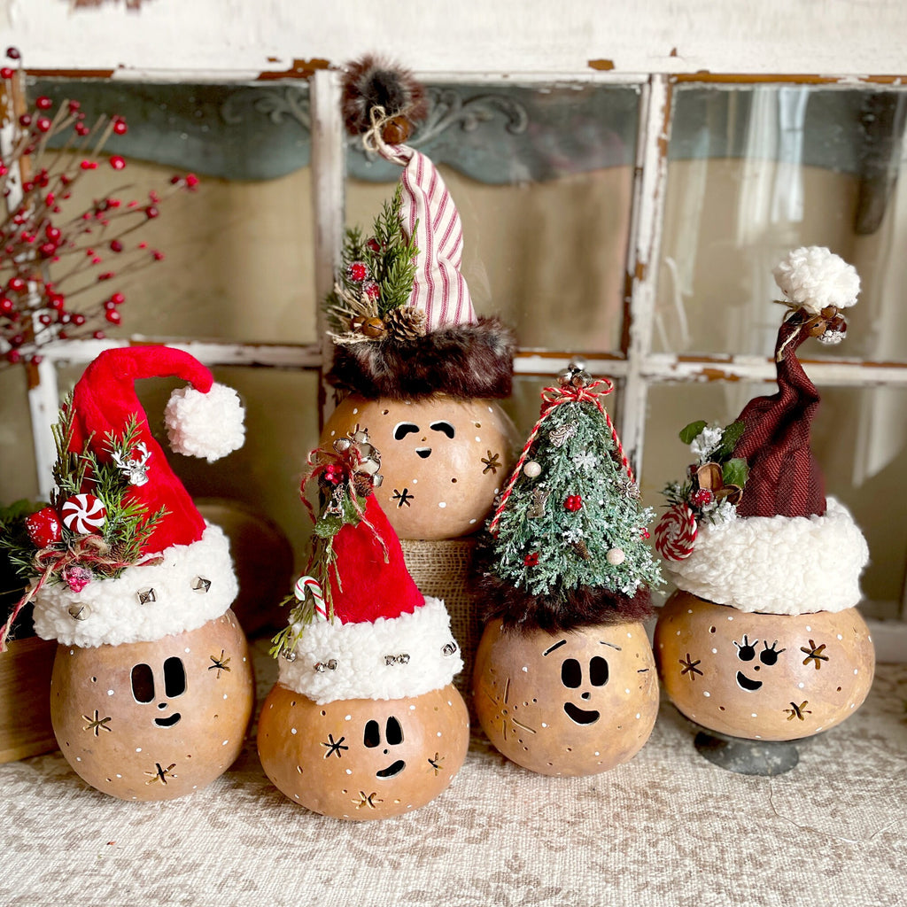 Decorative Christmas pots with faces and festive hats on a textured surface.