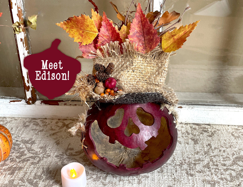Decorative skull with autumn leaves and a candle on a textured surface.