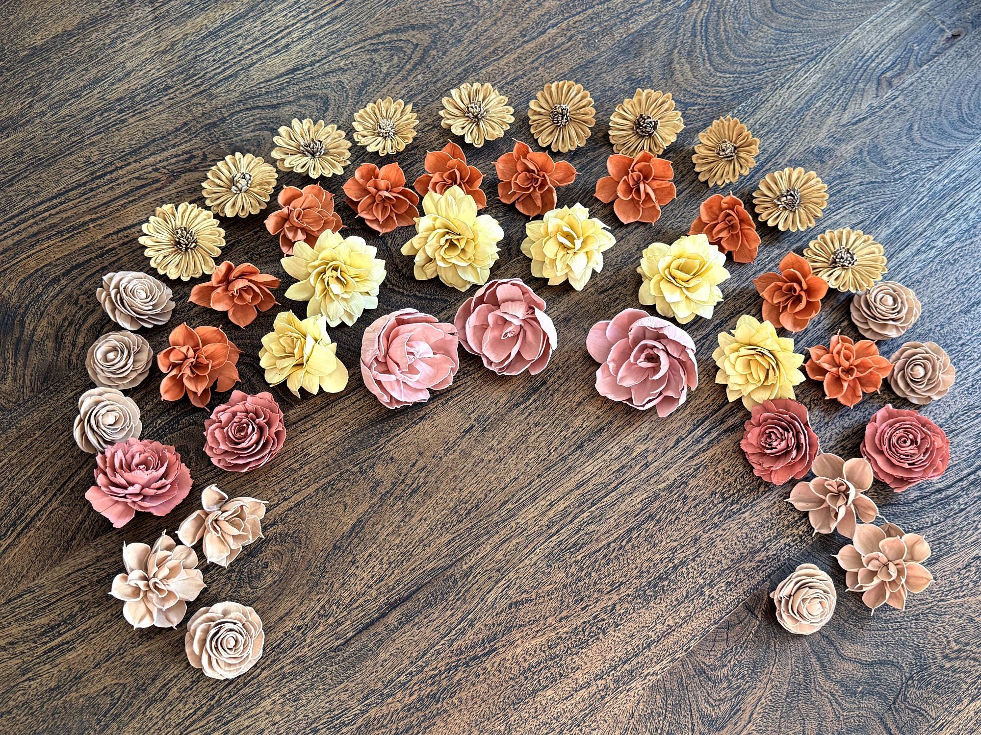 Decorative wood flowers arranged in a moon shape on a wooden surface
