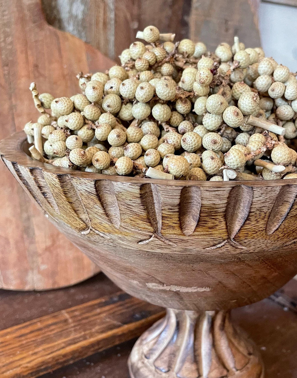 Wooden bowl filled with natural dried berries on a wooden surface