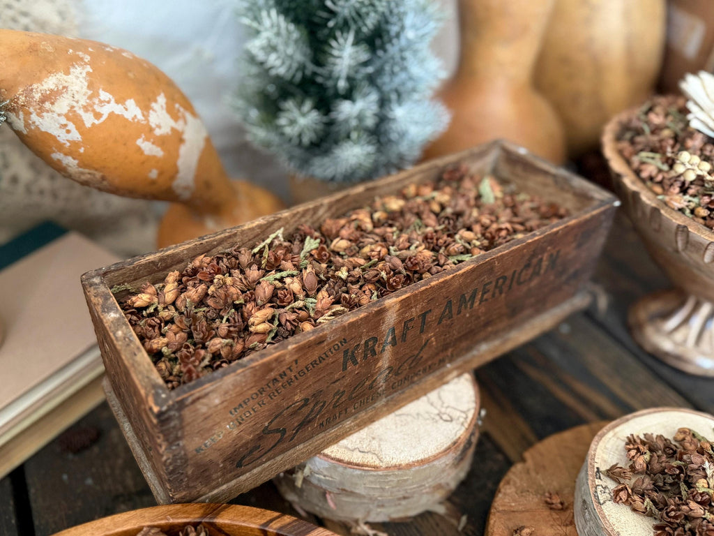 Wooden box with dried plants labeled 'Kraft America' surrounded by pumpkins and decorative items.