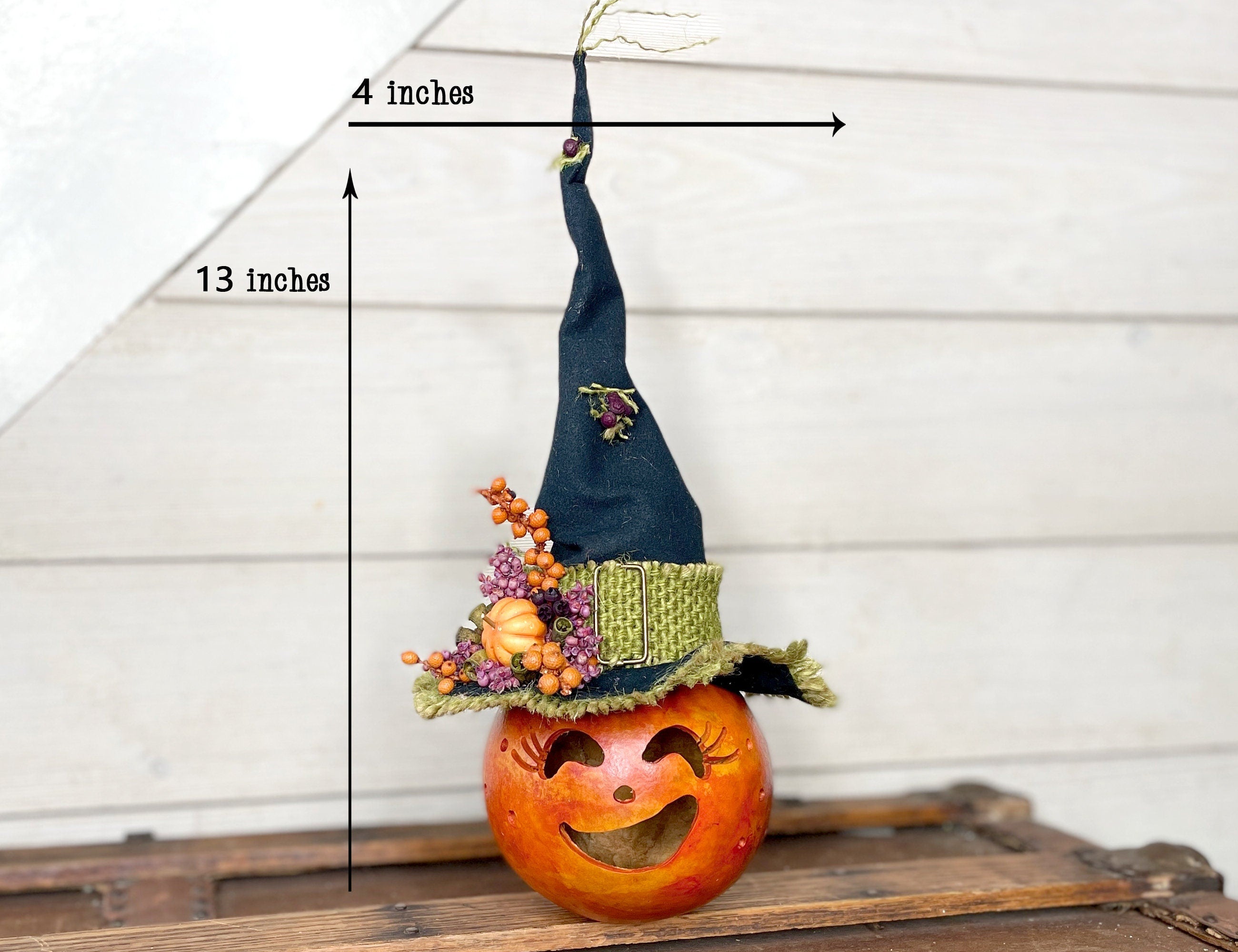 Pumpkin with a witch hat and measurements on a wooden surface