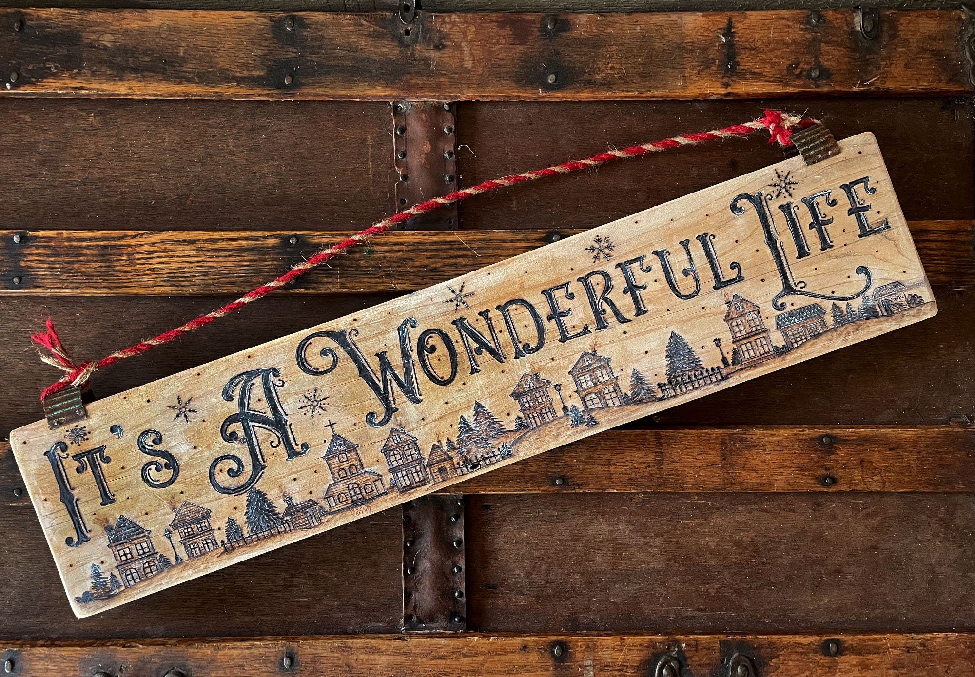 Decorative wooden sign with 'It's a Wonderful Life' text on a rustic wooden background.