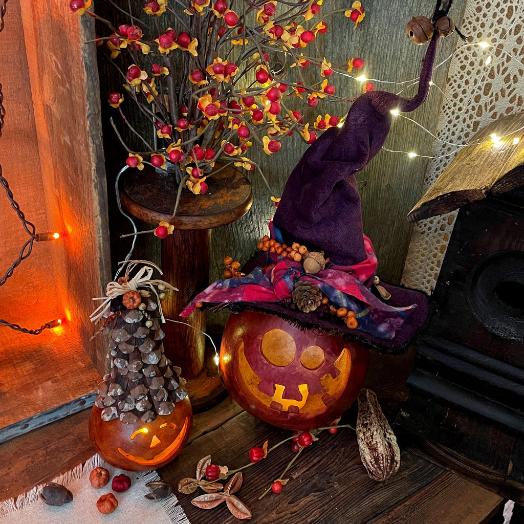 Decorative Halloween scene with pumpkins, a witch hat, and string lights.