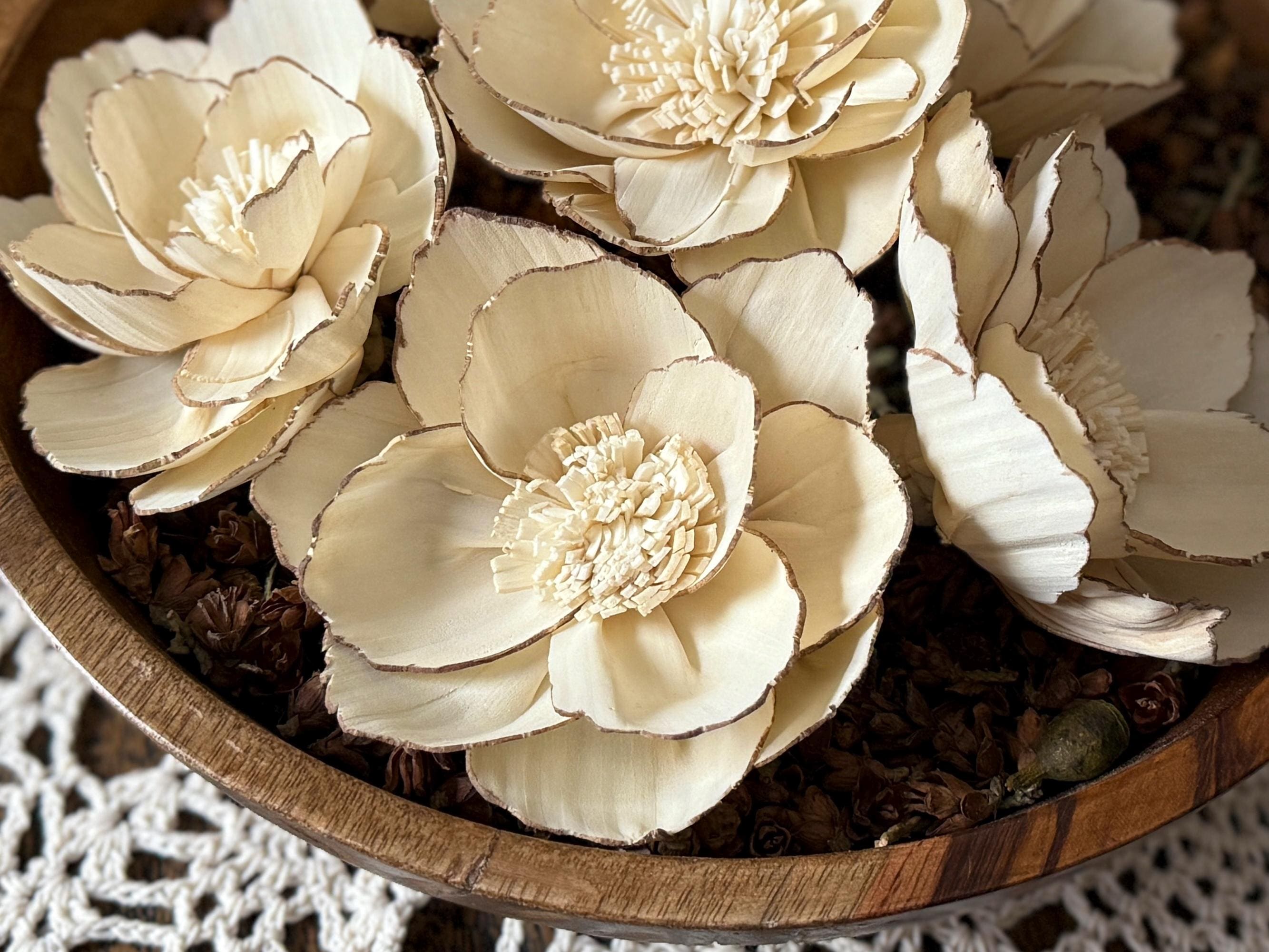 Wooden bowl filled with beige floral arrangements on a textured surface