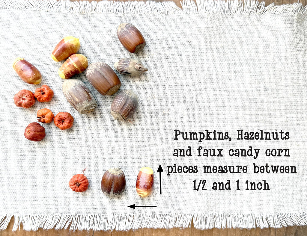 Assorted pumpkins, hazelnuts, and candy corn pieces on a textured white surface with text indicating measurements.