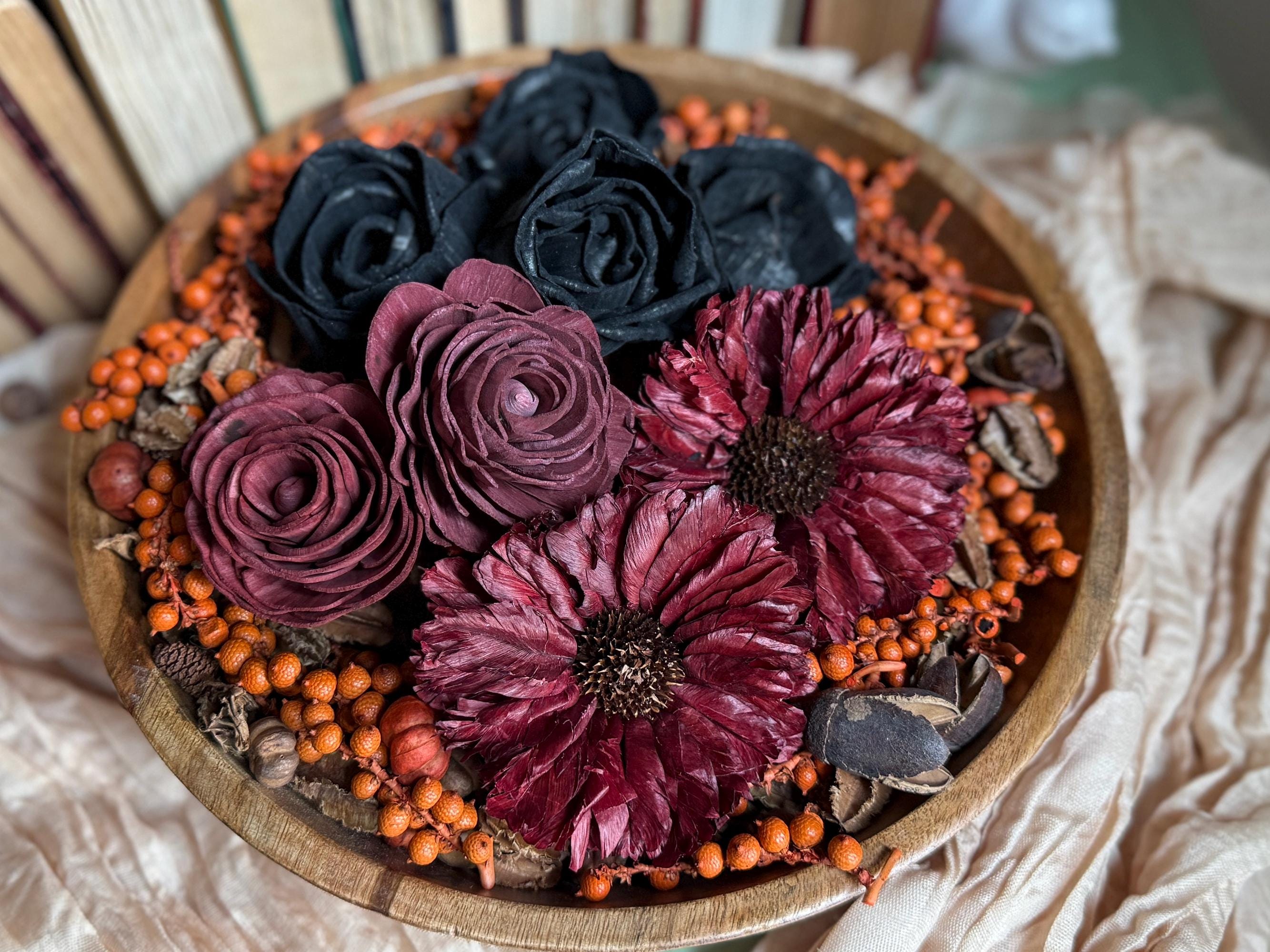 Decorative arrangement of wood flowers and berries in a wooden bowl.