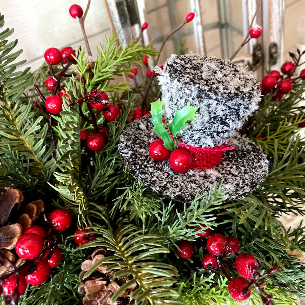 Decorative arrangement with greenery, red berries, and a small birdhouse.