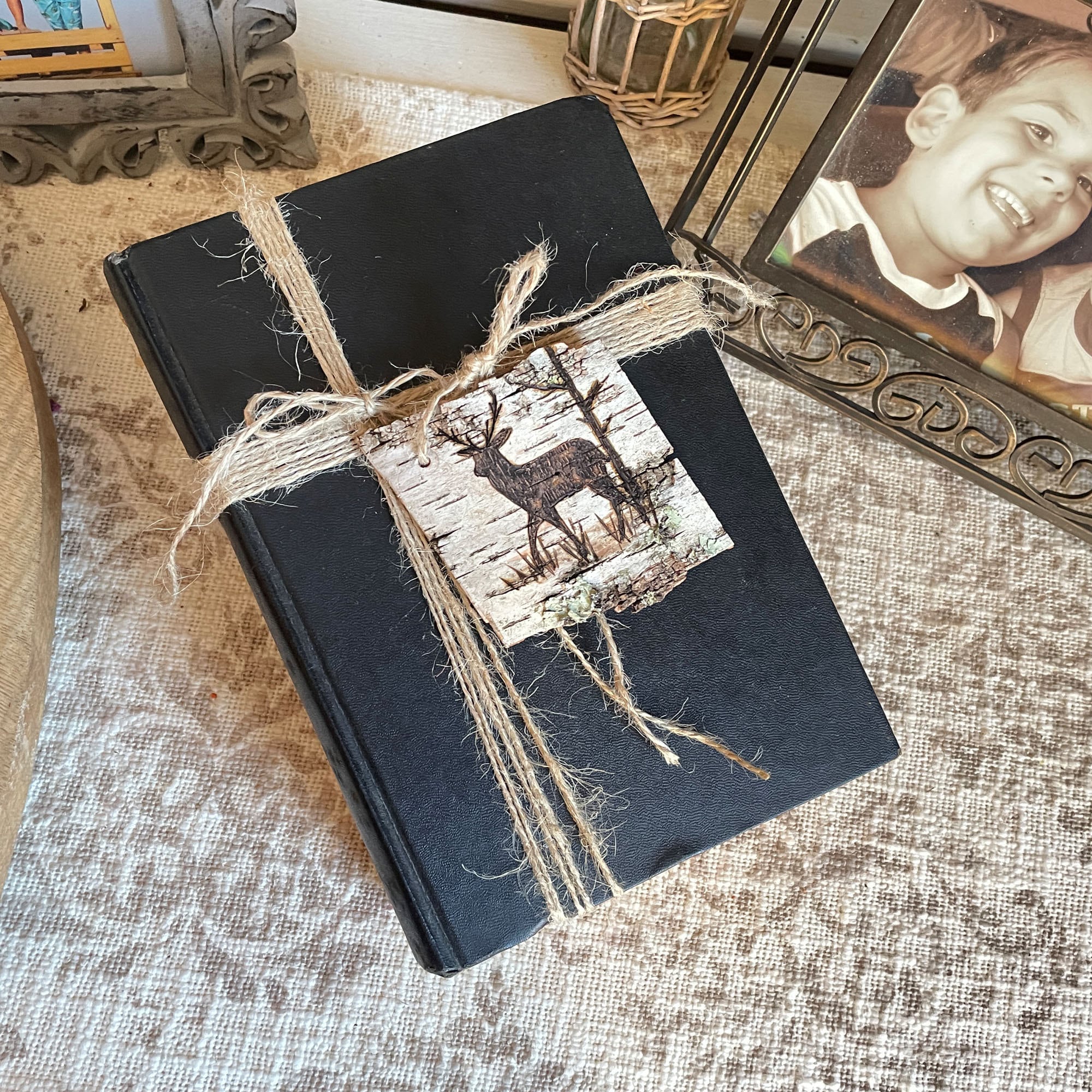 Black book with a deer tag design and twine on a textured surface