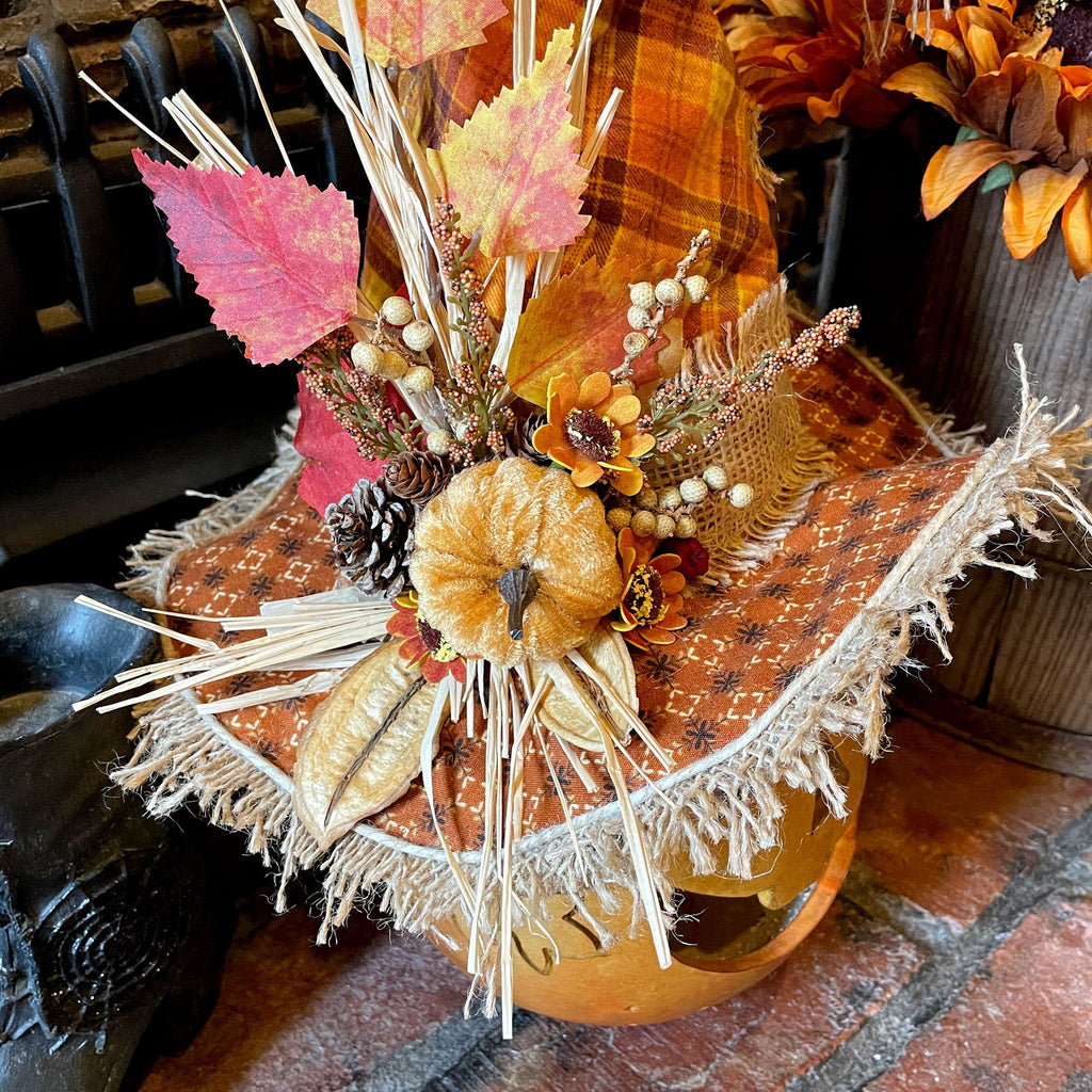 Decorative fall arrangement with pumpkins, leaves, and pinecones on a rustic surface.