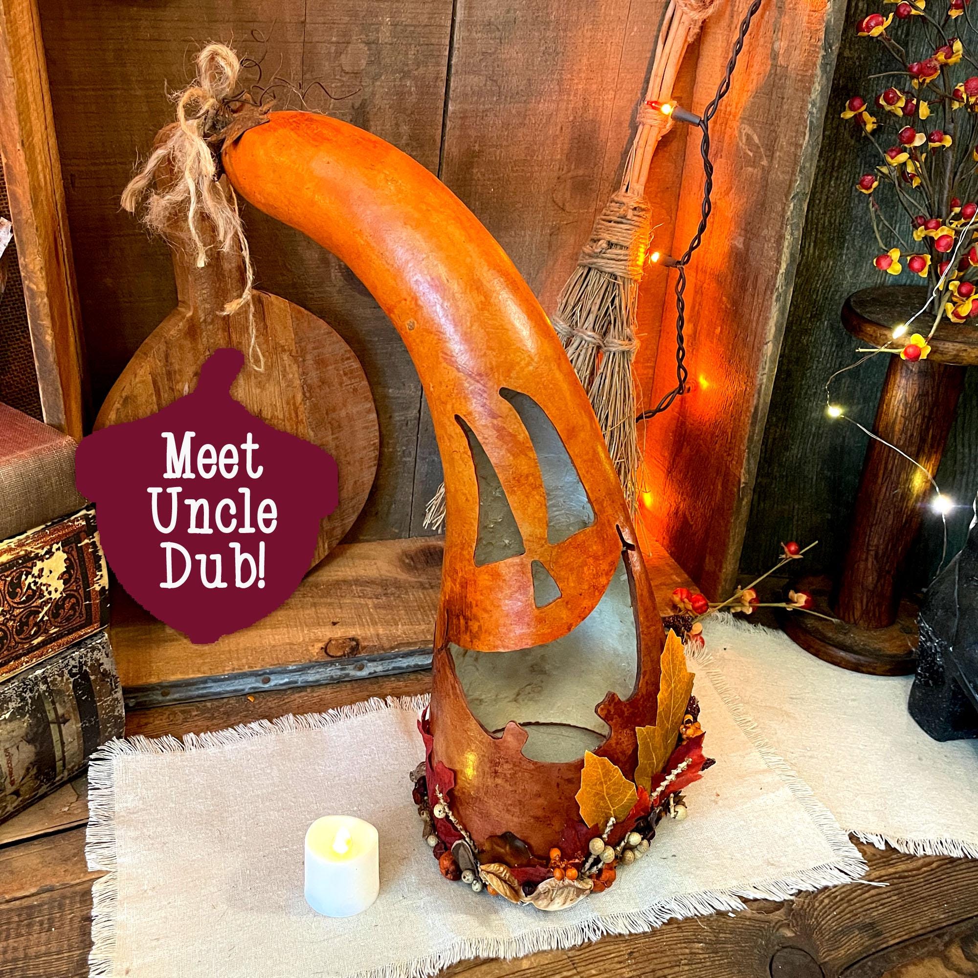 Decorative wooden pumpkin with a candle inside, surrounded by autumn-themed elements on a rustic background.
