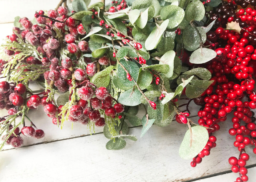 Decorative arrangement of red berries and green leaves on a wooden surface
