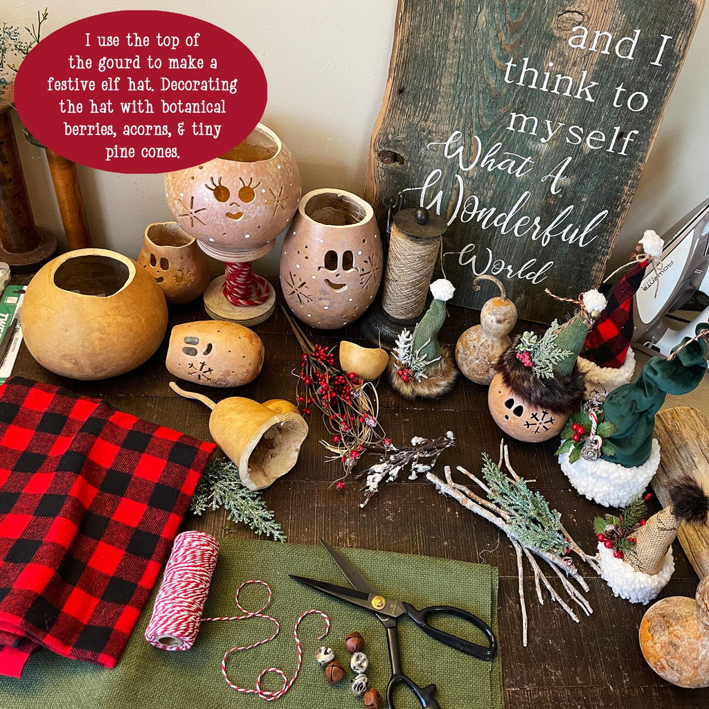 Decorative gourds with face designs on a table with craft supplies and a chalkboard sign.