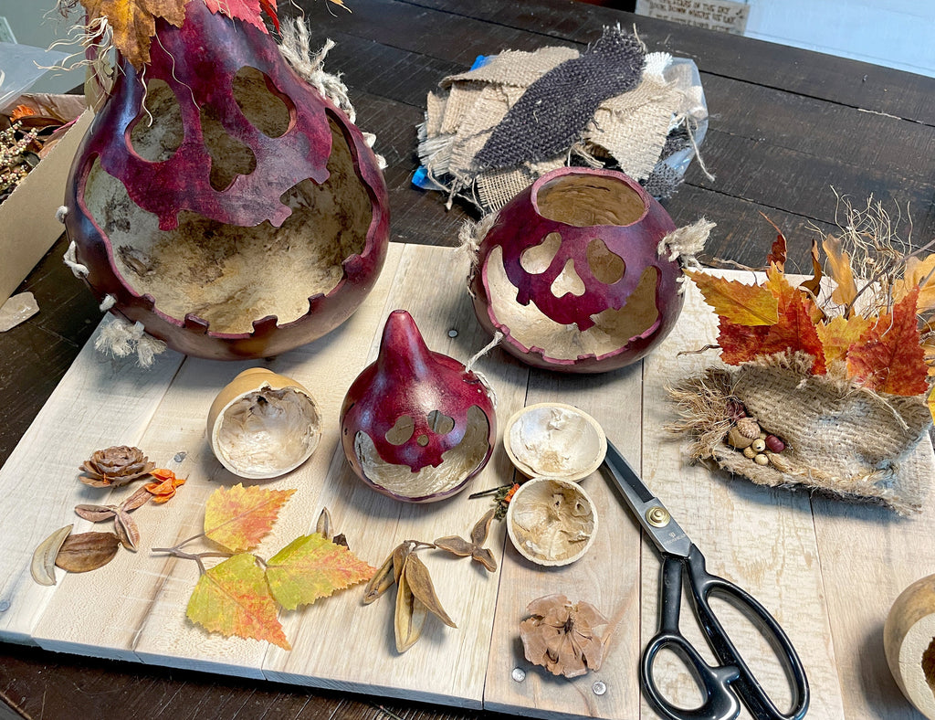 Artistic arrangement of dried plants, leaves, and decorative items on a wooden surface with scissors.
