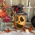 Decorative Halloween pumpkin with a top hat and autumn leaves on a rustic surface.