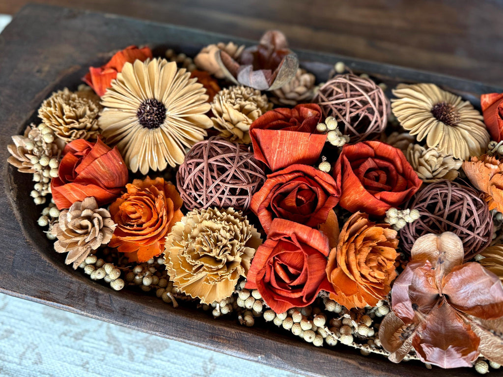 Decorative arrangement of dried botanicals and wood flowers on a coffee table.