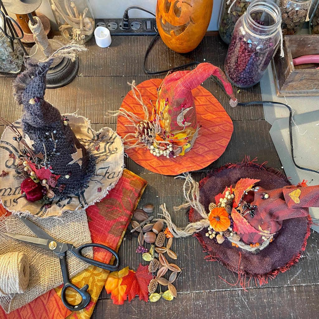 Halloween-themed decorations on a table with a witch hat, scissors, and pumpkins.