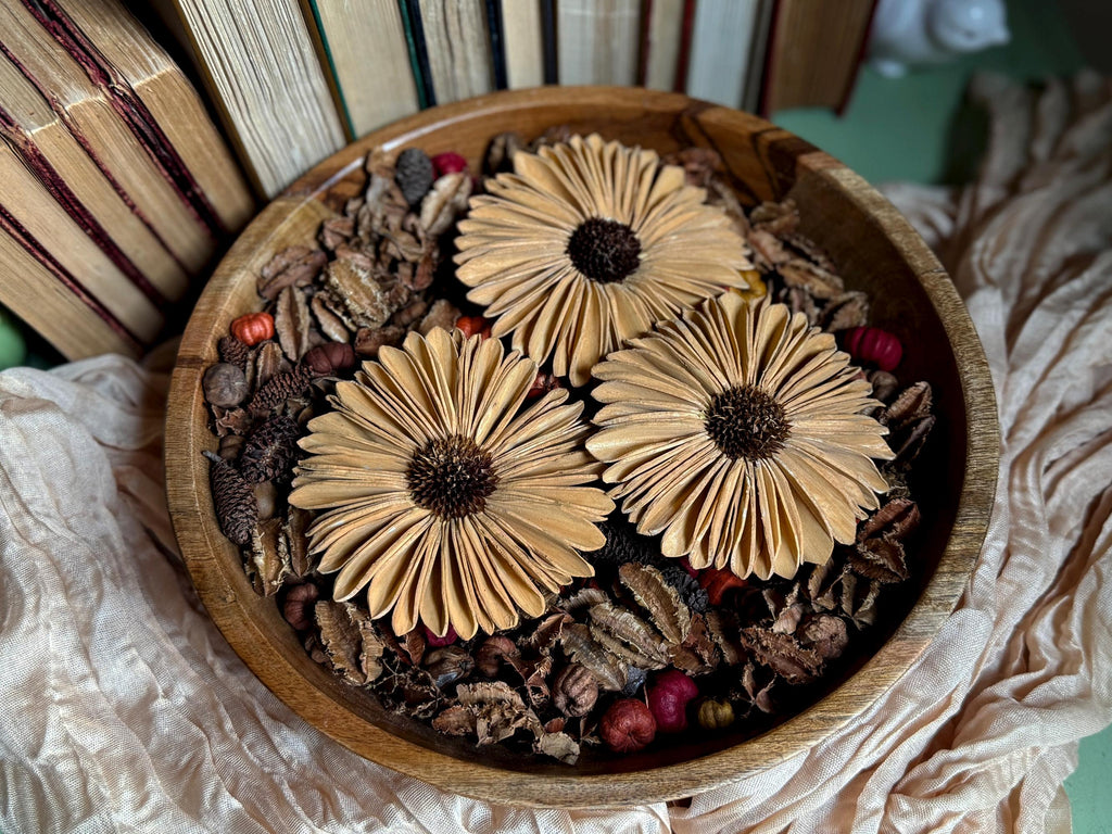 Wooden bowl with decorative flowers and natural elements on a textured surface