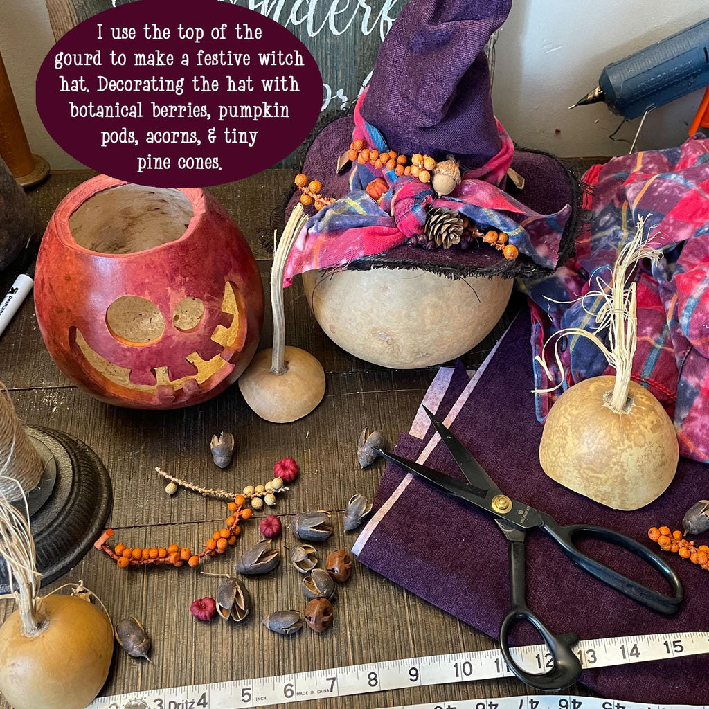 Decorative witch hat made from a gourd with botanical decorations on a table.
