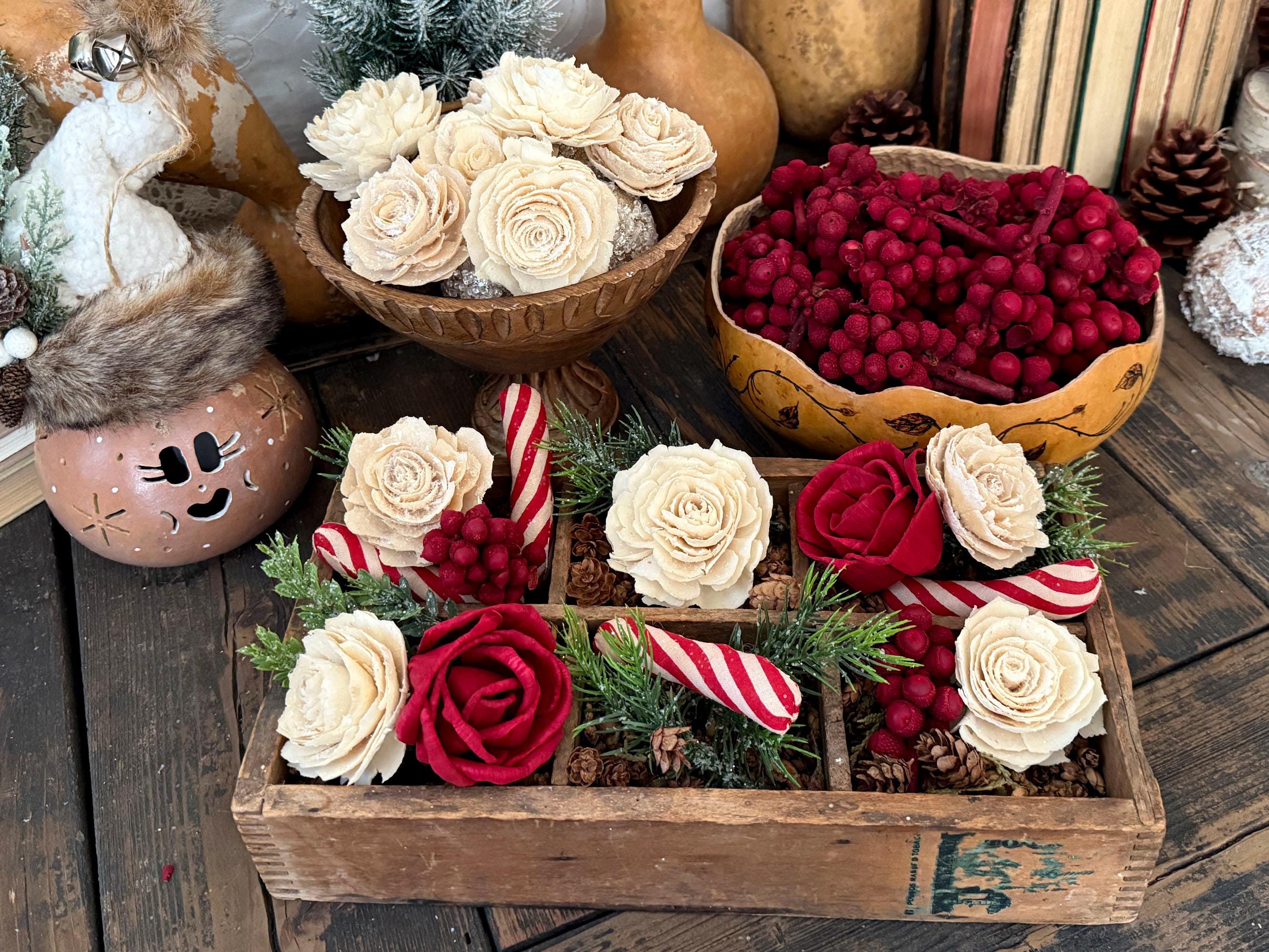 Decorative display with flowers, berries, and candy canes on a wooden surface.