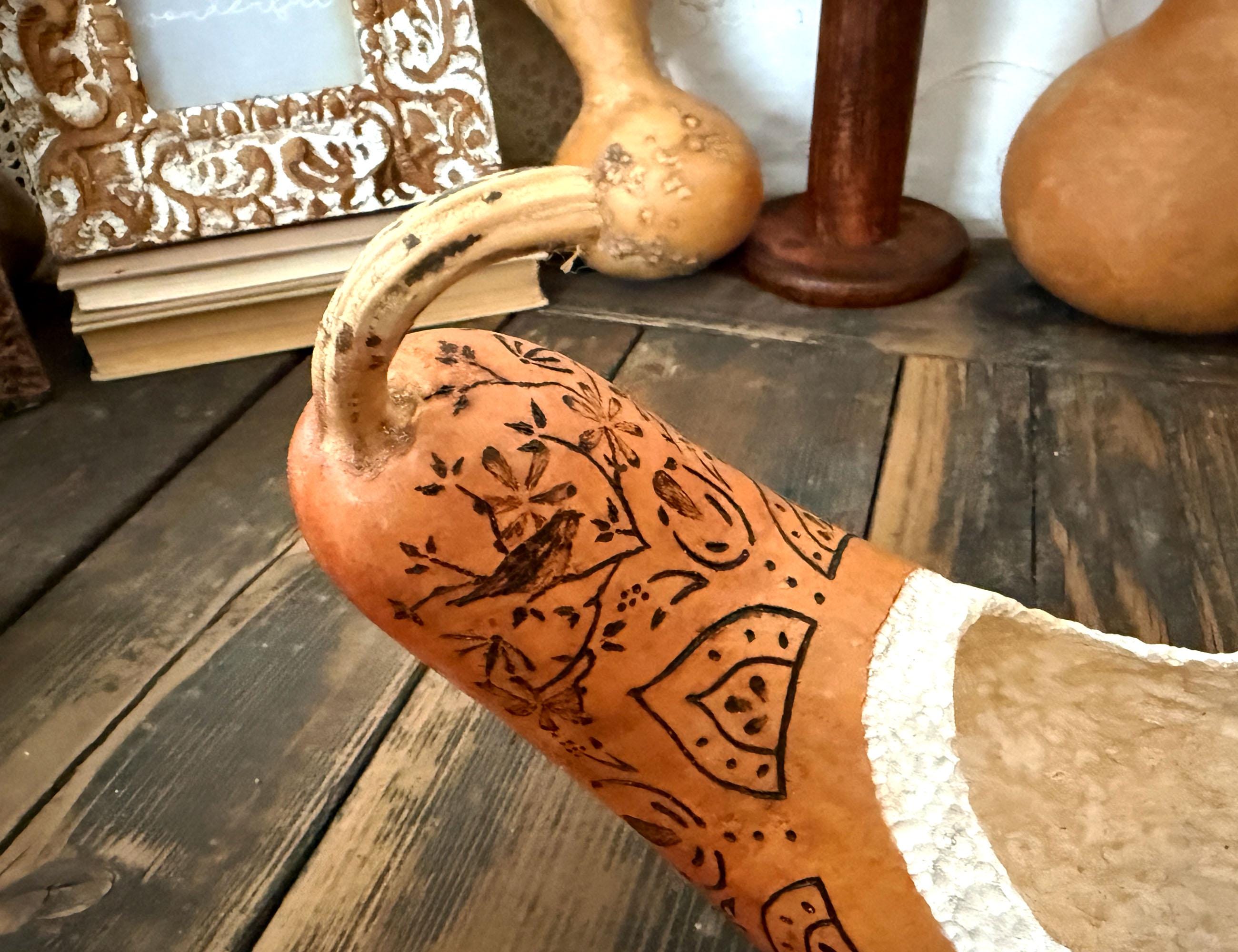 Decorative gourd with intricate black designs on a wooden surface