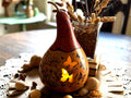 Decorative gourd with cat and butterfly designs on a table with a blurred background