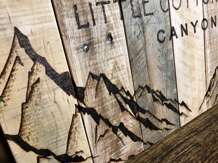Wooden sign with mountain design and 'Little Cotton Canyon' text