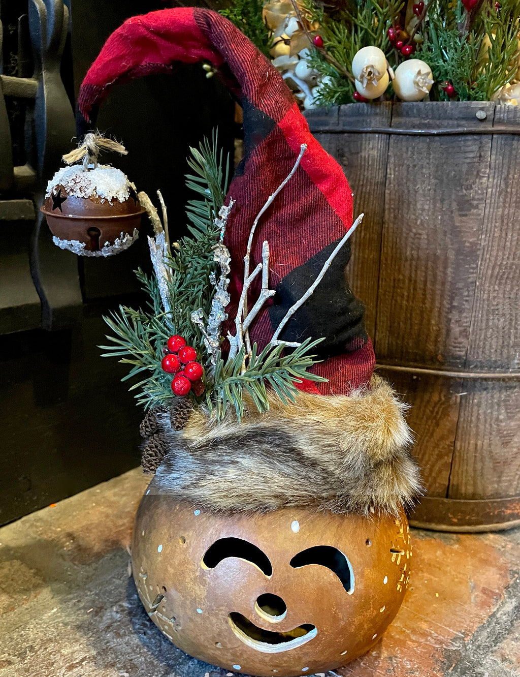 Decorative pumpkin with a face, fur trim, and plaid hat on a wooden surface.