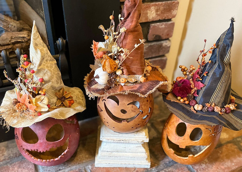 Three decorative pumpkins with witch hats on a stone surface.