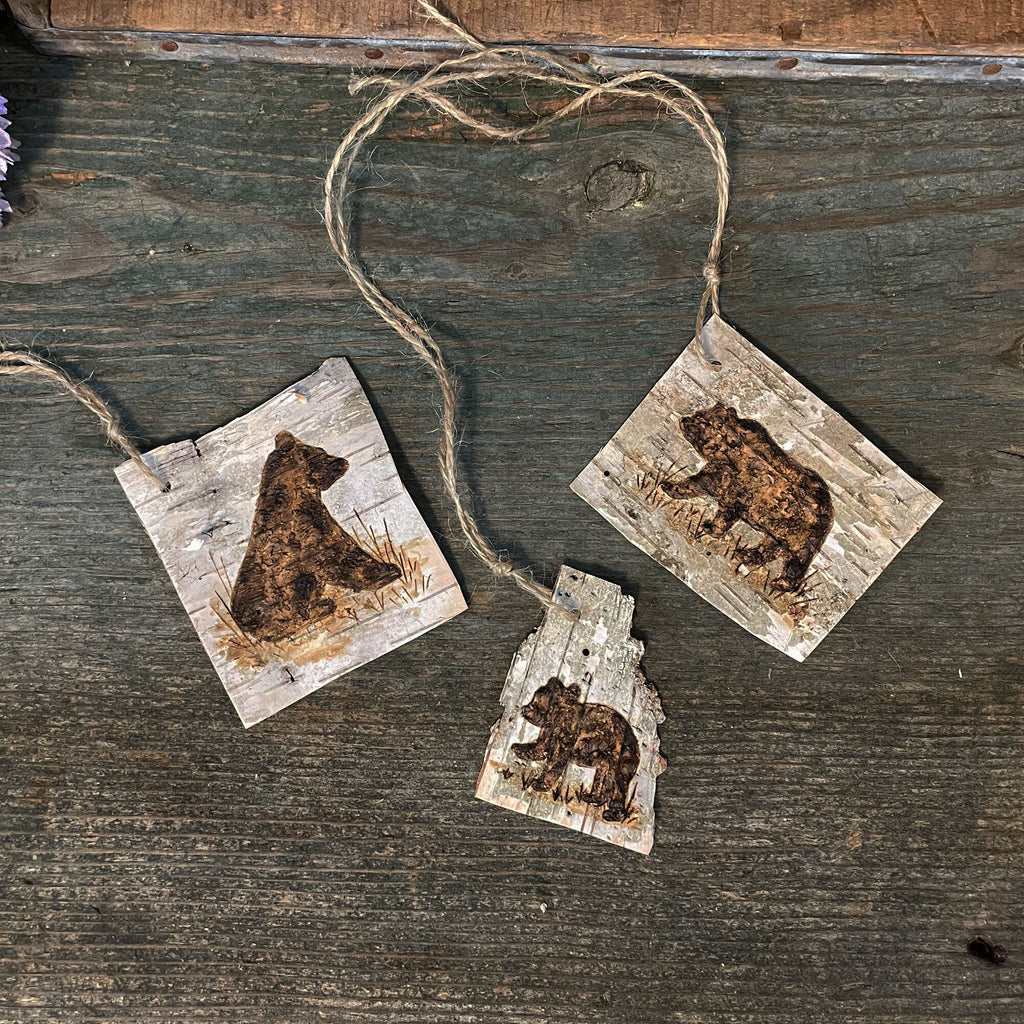 Three wooden bear tags hanging on a string against a rustic wooden background