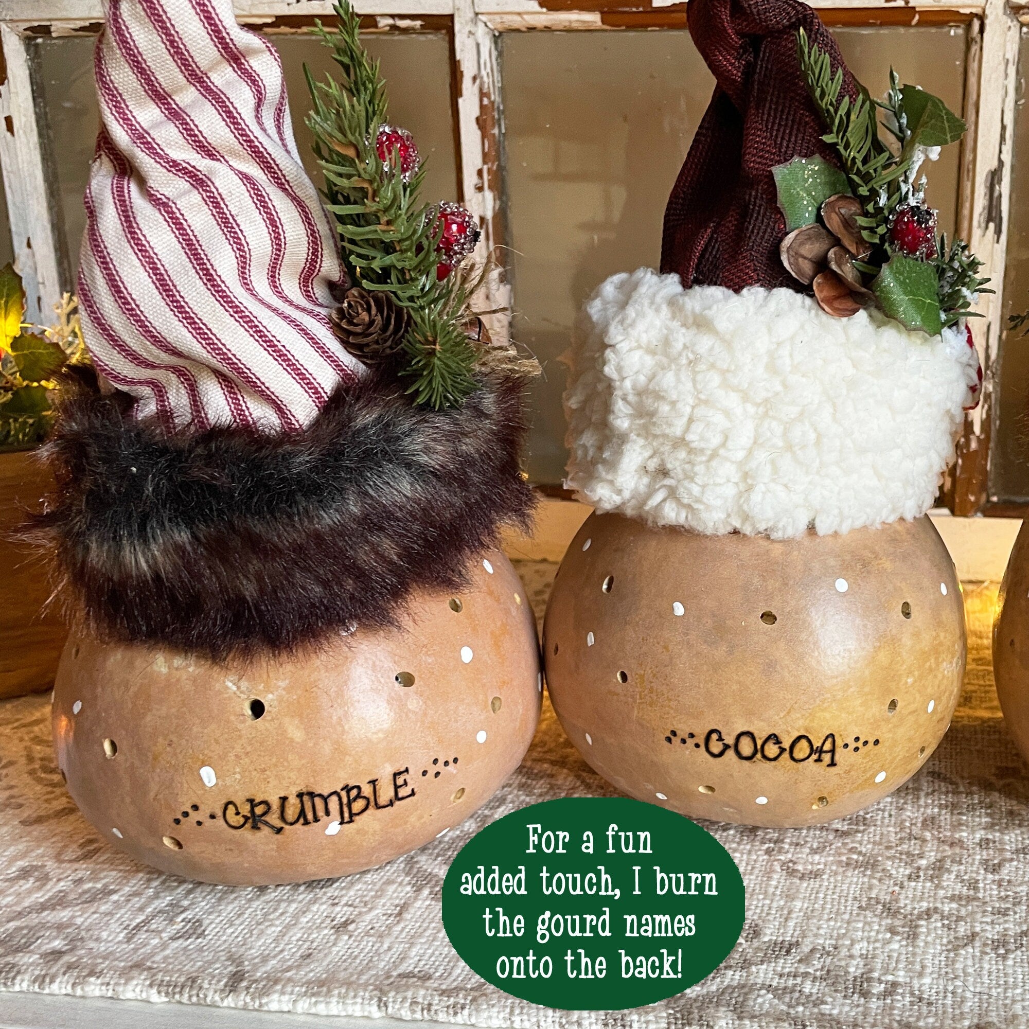 Two decorative gourds with fur and plant toppings, labeled 'Crumble' and 'Cocoa', on a rustic surface.