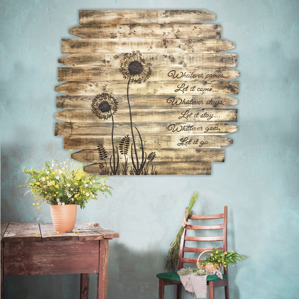 Wooden wall art with dandelion design and text on a light blue wall, with a table and chair in the foreground.