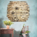 Wooden wall art with dandelion design and text on a light blue wall, with a table and chair in the foreground.