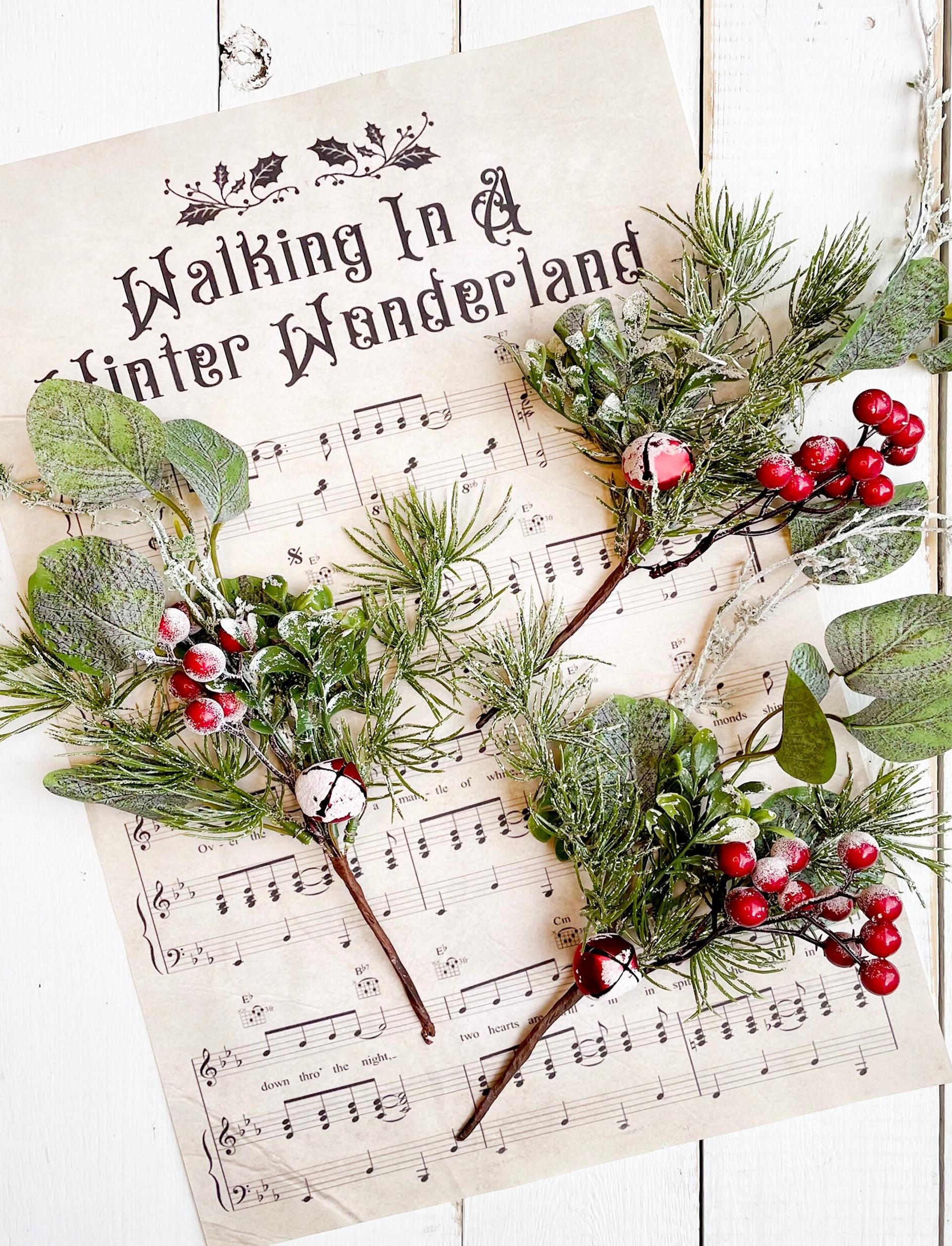 Christmas decorations with greenery and red berries on a sheet of music.