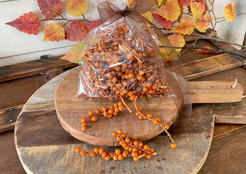 Packaged autumn-themed decor items on a wooden surface with fall leaves.
