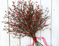 Decorative wreath with red berries and a pink ribbon on a white wooden background