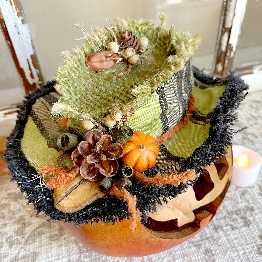 Decorative pumpkin with autumn-themed decorations on a textured surface.