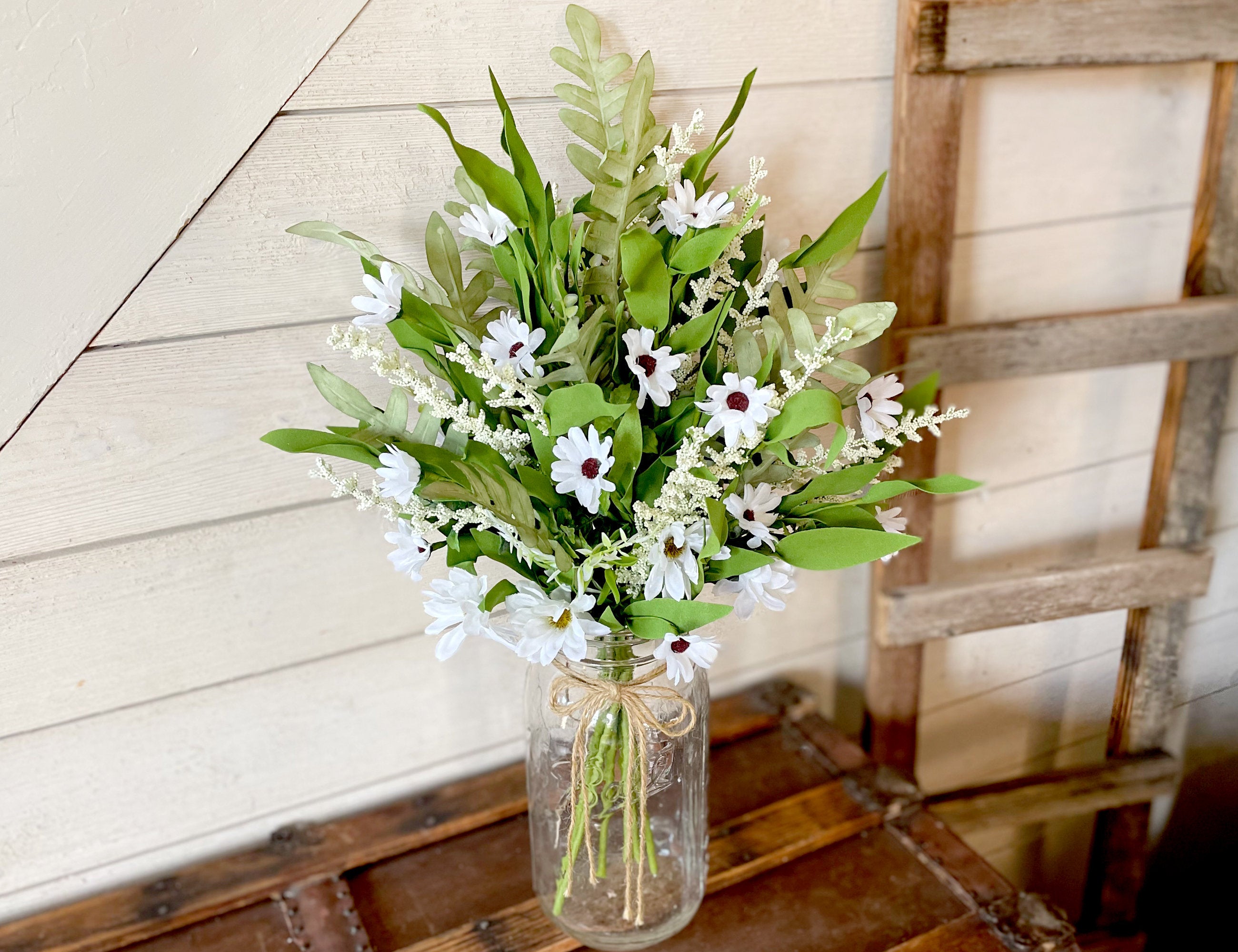 Bouquet of flowers in a glass jar on a wooden surface with a rustic background