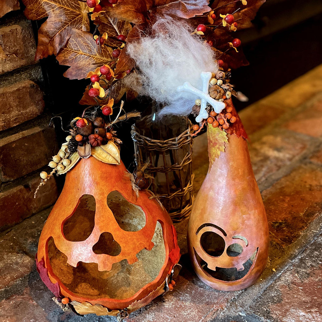 Decorative gourds with jack-o'-lantern faces on a stone surface.