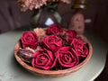 Red roses in a wooden bowl on a table with a blurred background
