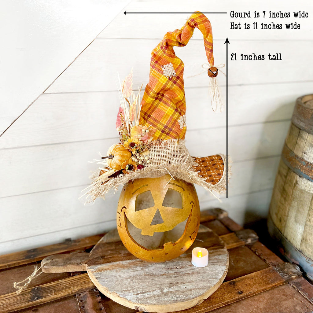 Decorative Halloween pumpkin with plaid hat on a wooden surface, measurements indicated.