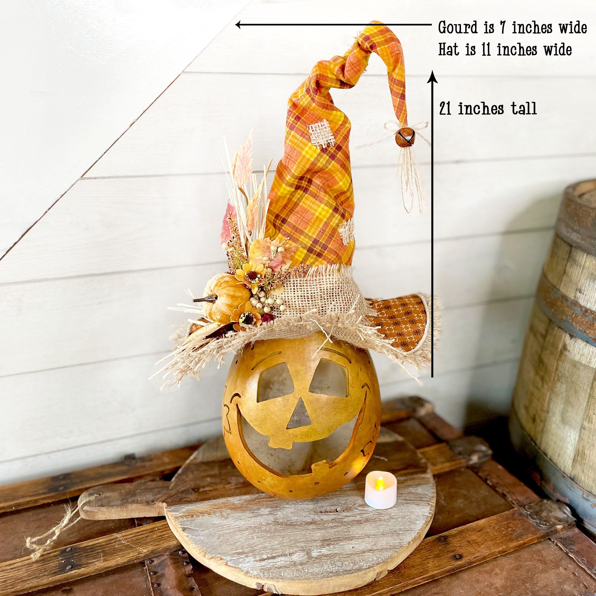 Decorative Halloween pumpkin with plaid hat on a wooden surface, measurements indicated.