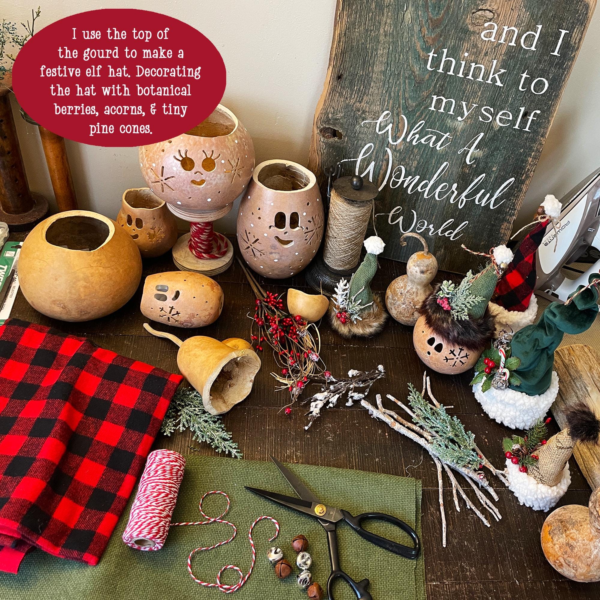 Decorative gourds with face designs on a table with craft supplies and a chalkboard sign.