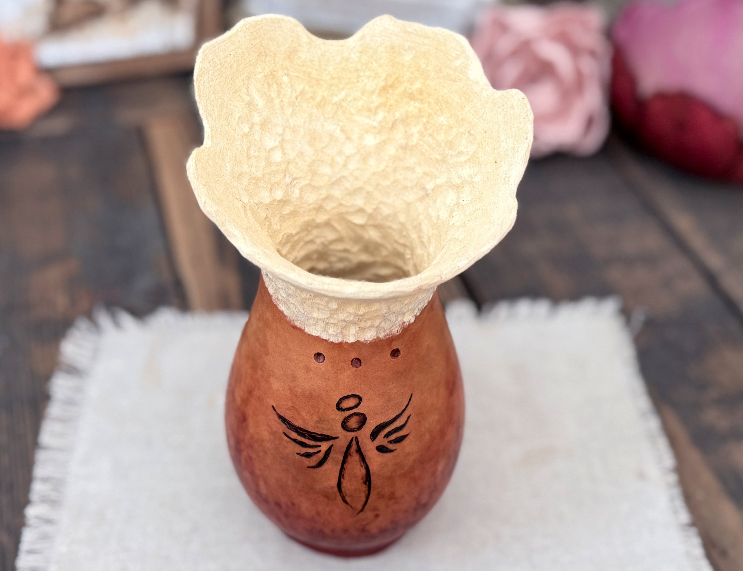 Decorative gourd vase with a textured stipple rim in beige and the bottom in a cherry brown with an Angel drawn on the front