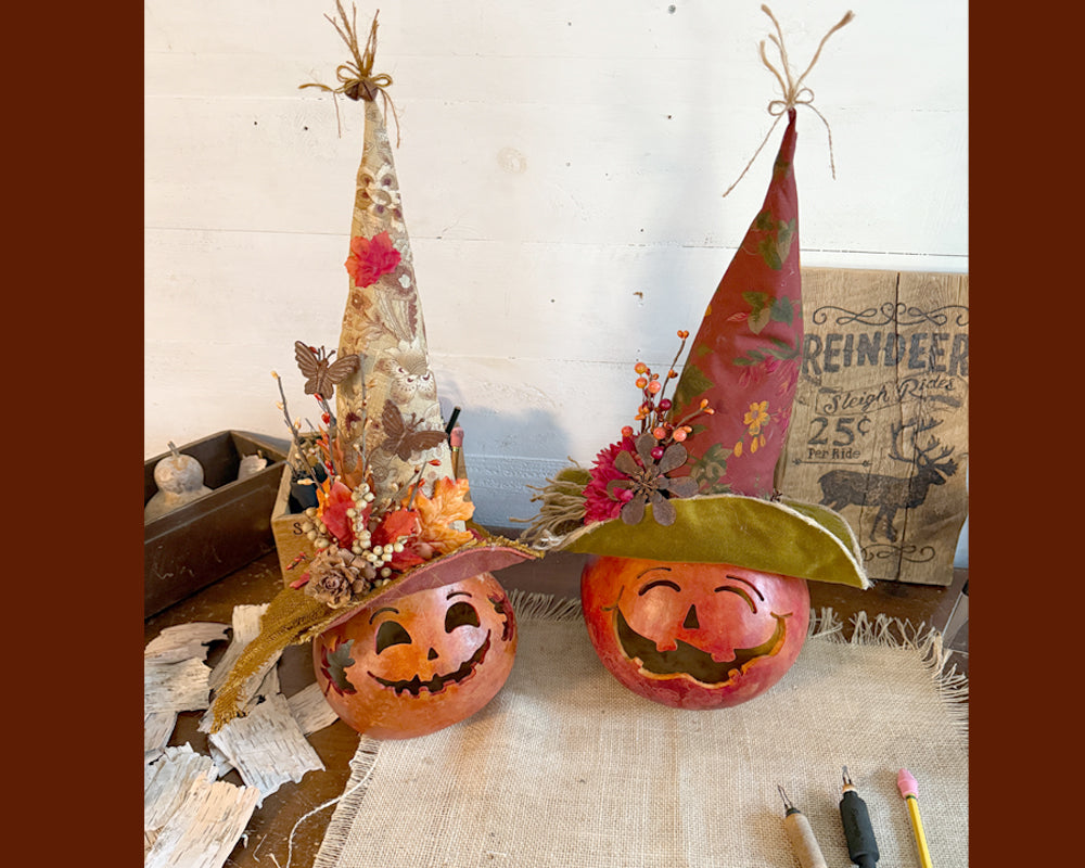 Two jack-o'-lanterns with decorative hats on a rustic surface.