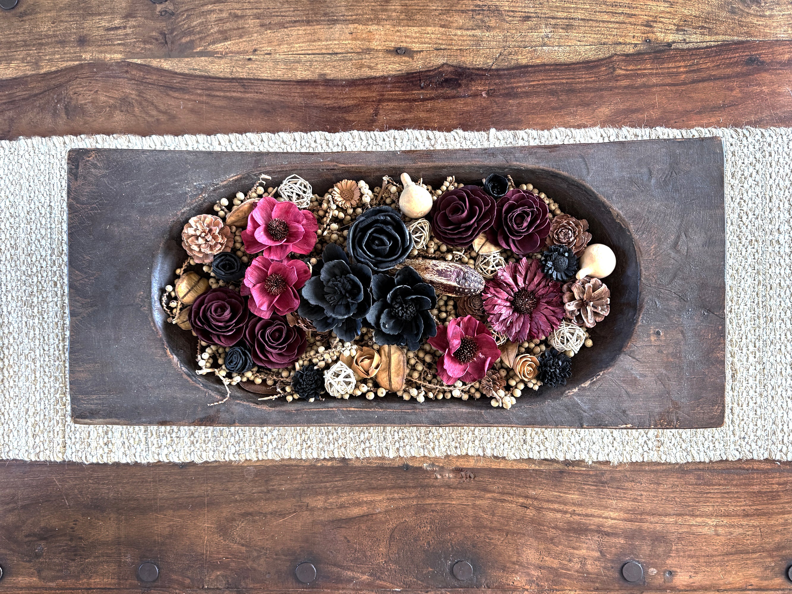 Decorative dough bowl arrangement of flowers and decorative elements on a coffee table.
