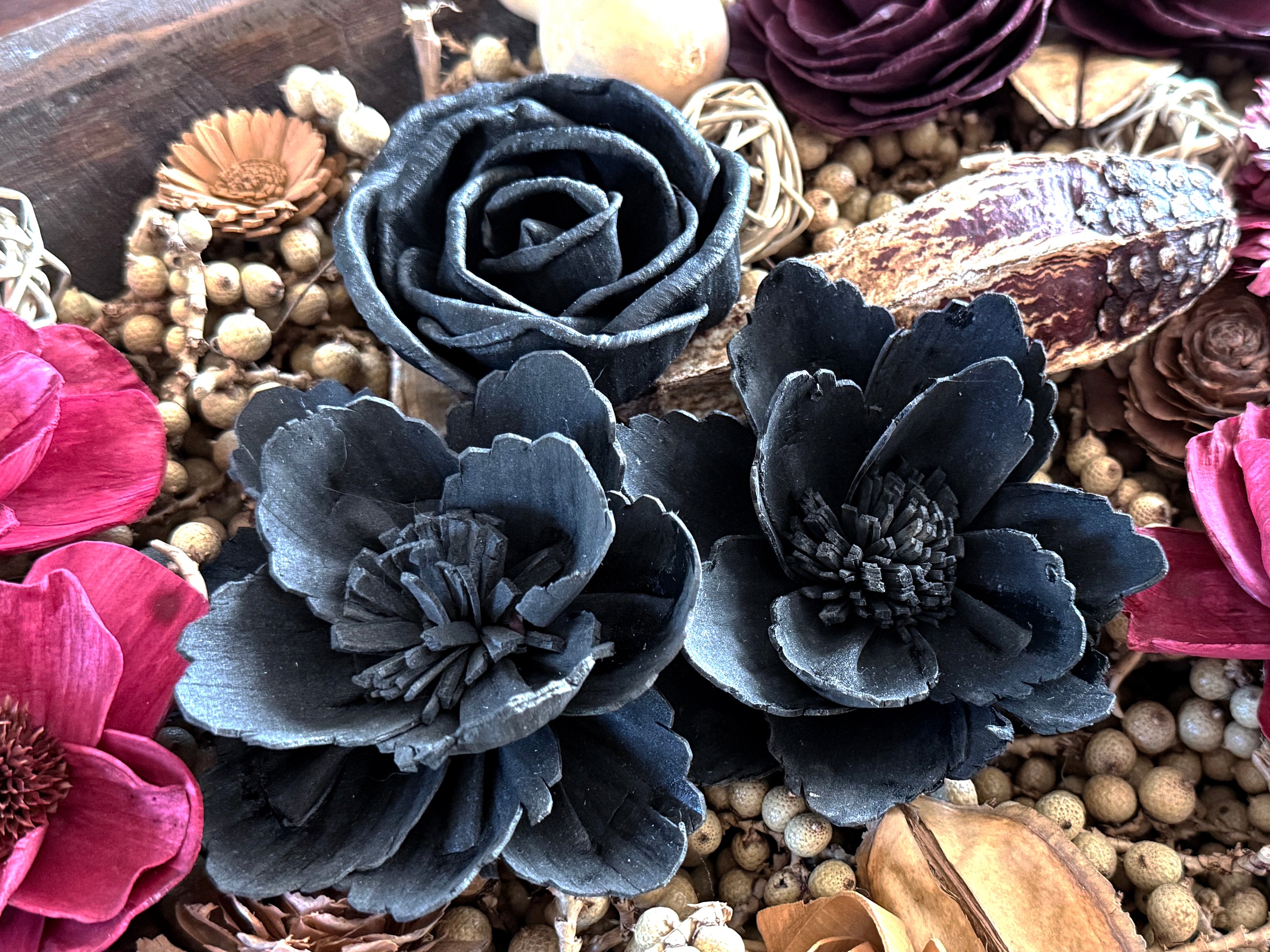 Decorative flowers in black and pink with a wooden bowl background