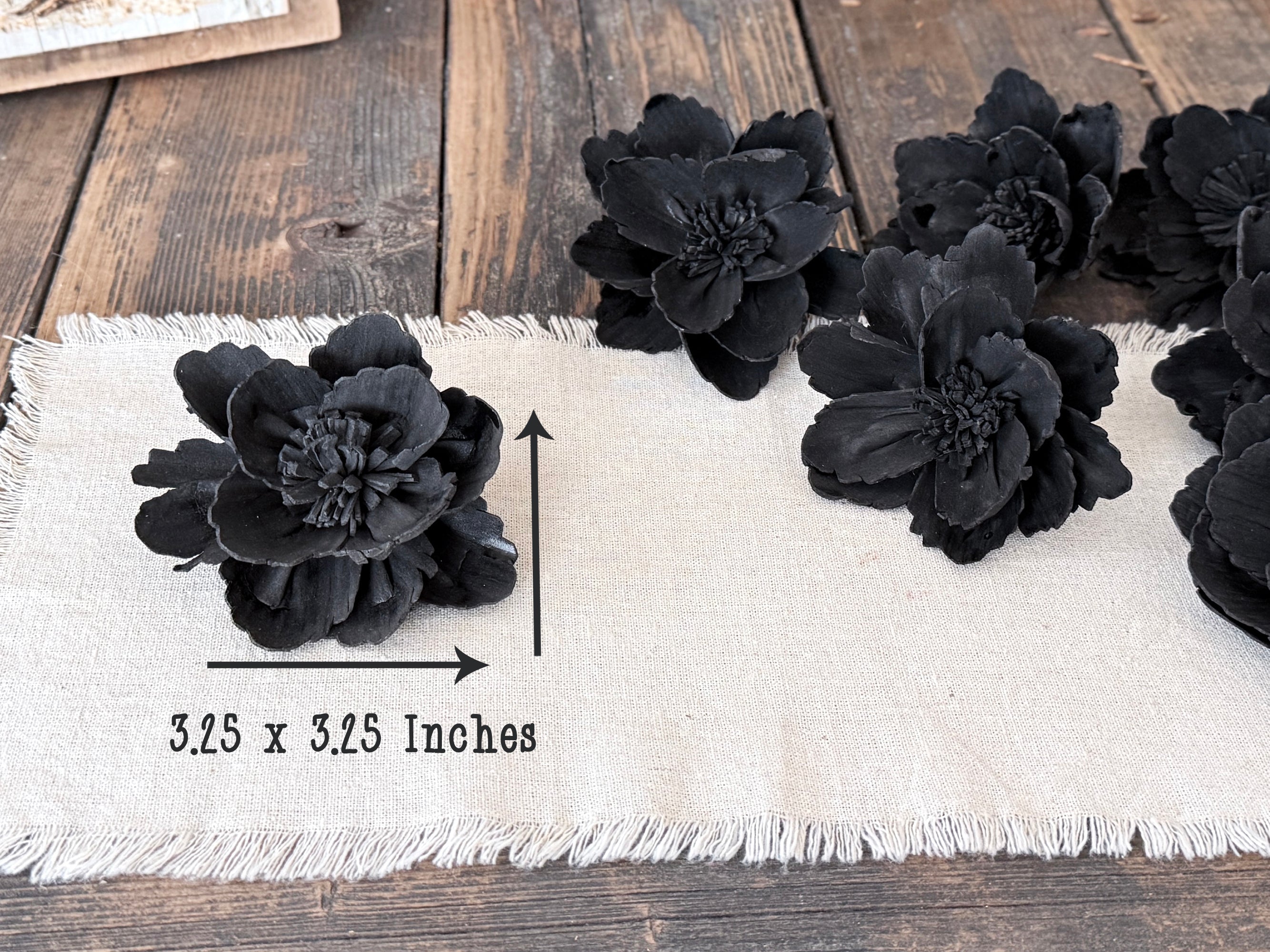 Black floral decorations on a white fabric strip with measurements on a wooden surface